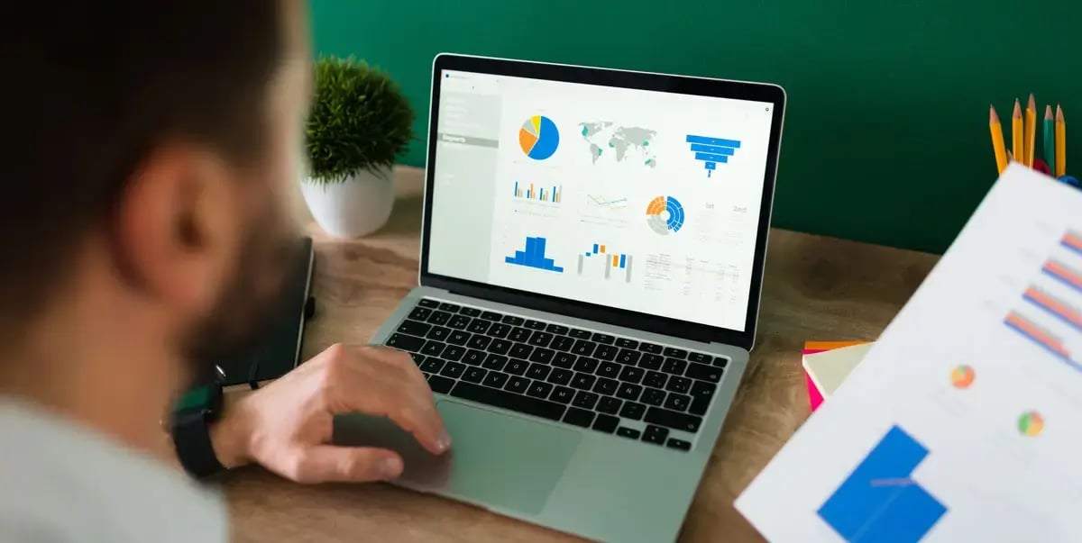 rear-view-young-man-working-his-laptop-looking-work-report-graphs